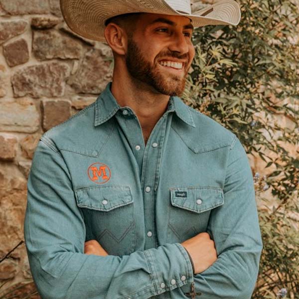 A man wearing a cowboy hat and blue shirt exudes a sense of ruggedness and style, capturing the essence of the Wild West.