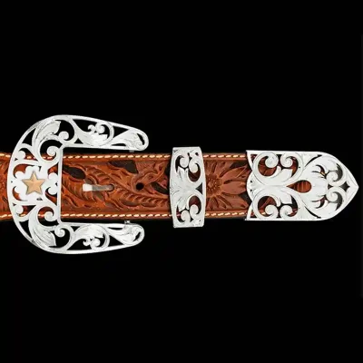 A custom western three piece belt buckle set featuring silver filigrane and a golden star figure 