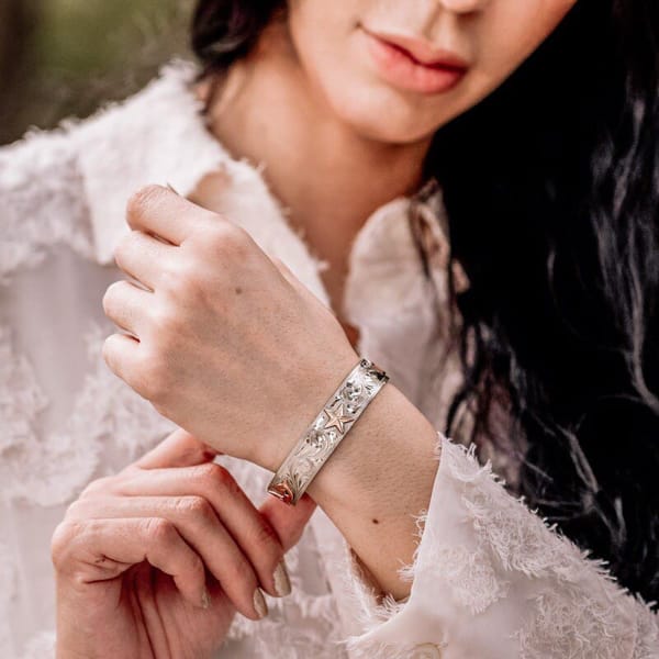 Woman wearing a silver western cuff bracelt with custom golden figure